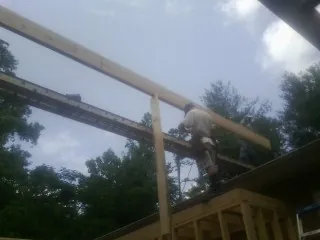 Carpenter setting a ridge beam over a new addition frame — Ice Dam Removal by Roofing Brothers in Mount Savage