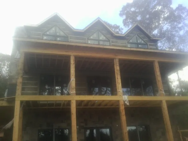Dormers and porch framing on a large log home under construction — Roof Coating work by our crew in Mount Savage