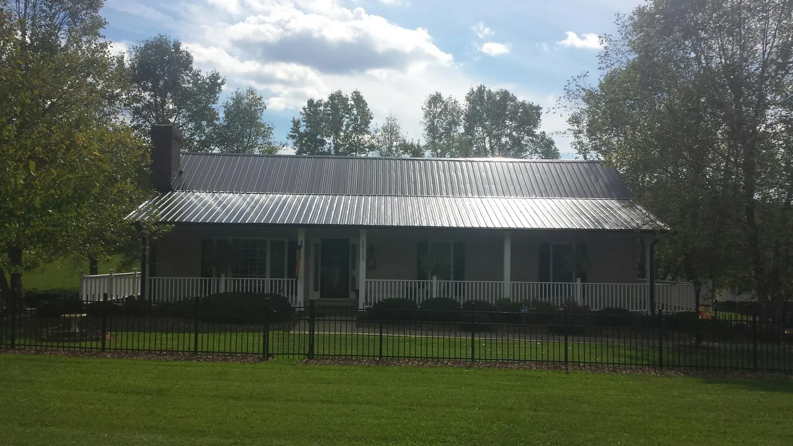 Gray metal roof on a brick ranch with a full width front porch — Gutter Guard Installation work by our crew in Mount Savage