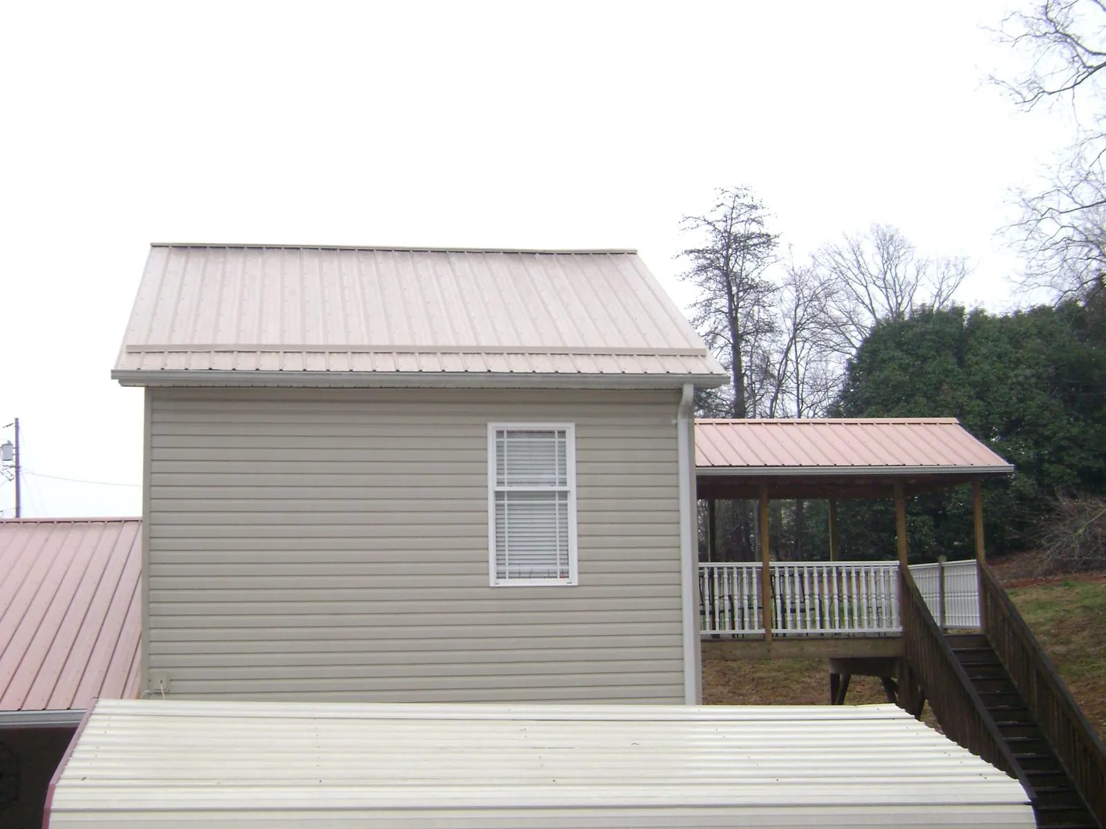 Tan metal roofs on a two story addition and attached porch, from a Roof Replacement job in Mount Savage